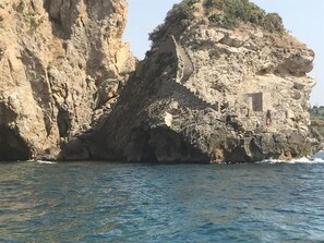 A rocky coastline with a small stone structure on a cliff. - Residence Eloisa (Balestrate)