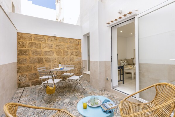 A small outdoor patio with a stone wall, a table with chairs, and a wicker chair. - Casa Loreto (Javea / Xàbia)