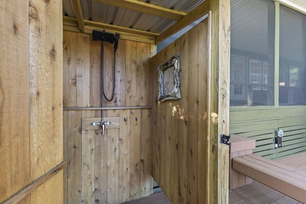 A wooden cabin with a shower, a rustic door, and a bench outside.