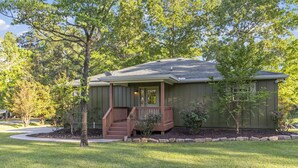 A single-story house with a front porch, a small staircase, and a well-maintained lawn.