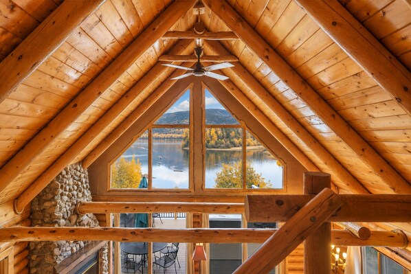 A wooden interior with a large window overlooking a lake and autumn trees.