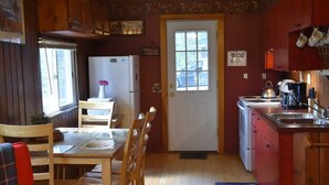 A compact kitchen with wooden cabinets, a refrigerator, a stove, and a sink.