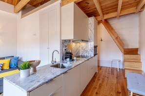 A modern kitchen with white cabinetry, a marble countertop, and a wooden ceiling. - S. Bento Apart IV (I) (Oporto)