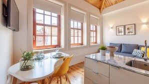 Una cocina moderna con techo de madera, ventanas amplias y una zona de comedor con mesa y sillas.