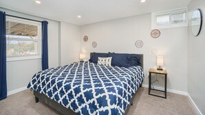 Une chambre à coucher comprenant un lit, deux tables de chevet, une fenêtre avec des rideaux et des éléments décoratifs sur les murs.