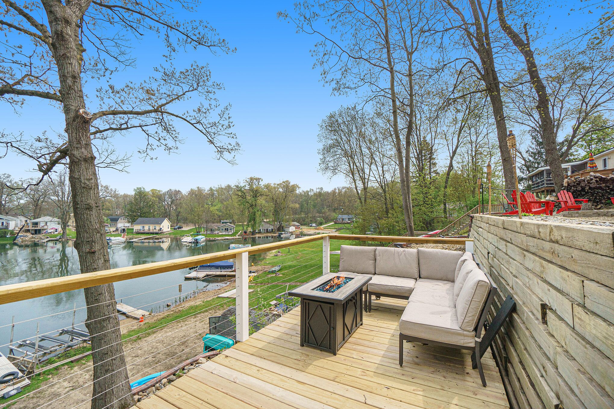 A deck with a fire pit, outdoor seating, and a view of a lake with boats.