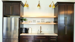 Una cocina moderna con armarios de madera oscura, un refrigerador de acero inoxidable, una cafetera integrada y una encimera de madera clara.