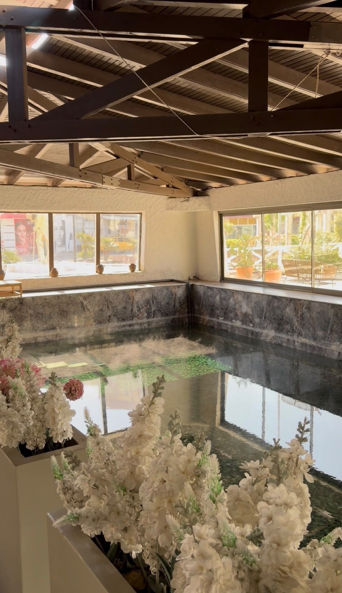 Área de spa com hidromassagem, paredes de mármore e amplas janelas.