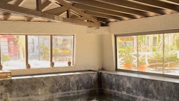 Área de spa com hidromassagem, paredes de mármore e amplas janelas.