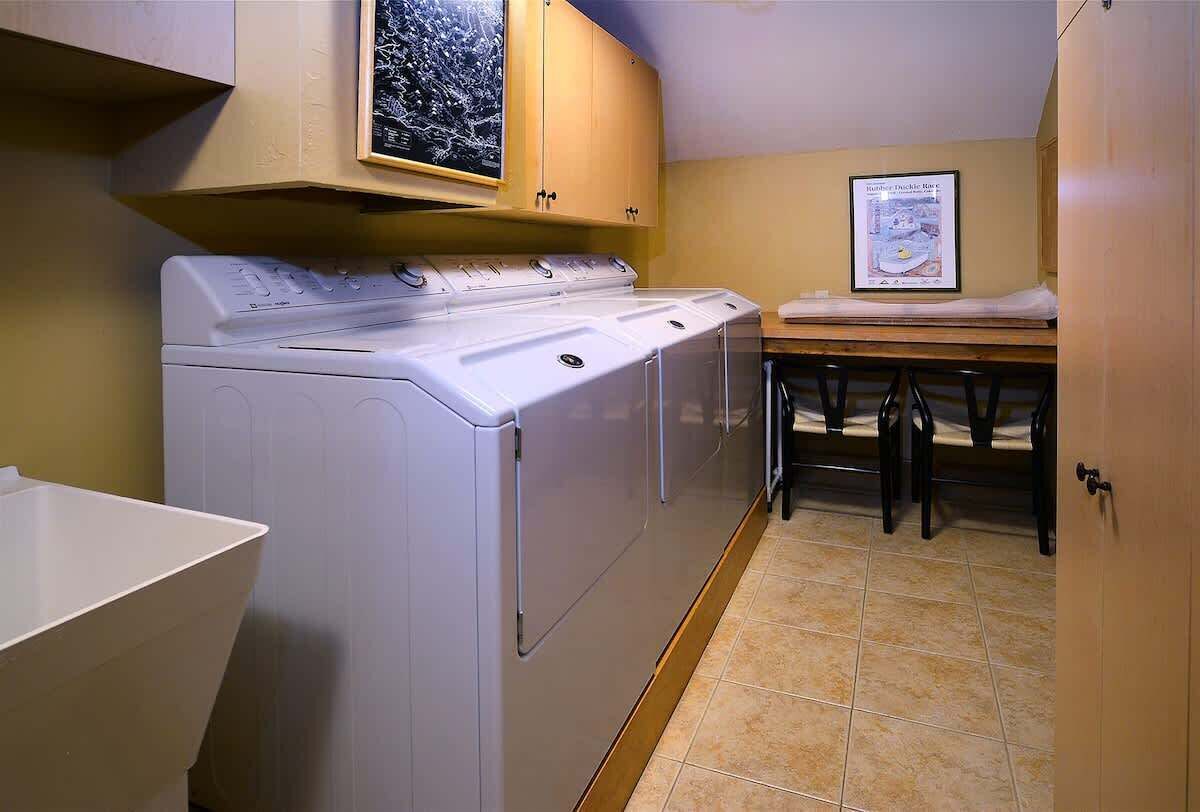 A laundry room with a washing machine, a drying rack, and a table with chairs.