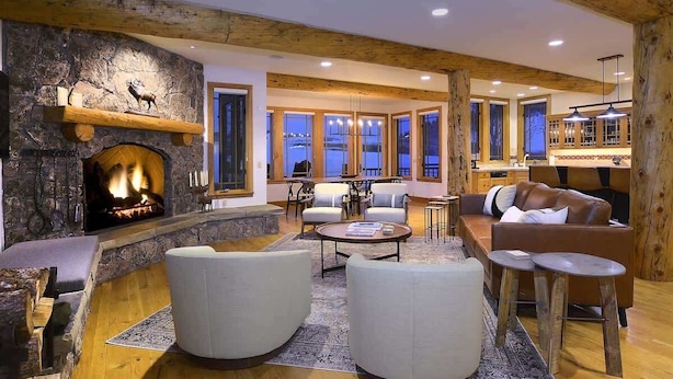 A cozy living room with a fireplace, comfortable seating, and a view of the outdoors. - Goldlink Lodge (Crested Butte)