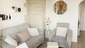 Un salon moderne comprenant un canapé, des fauteuils, une table à manger et un miroir décoratif de forme hexagonale.
