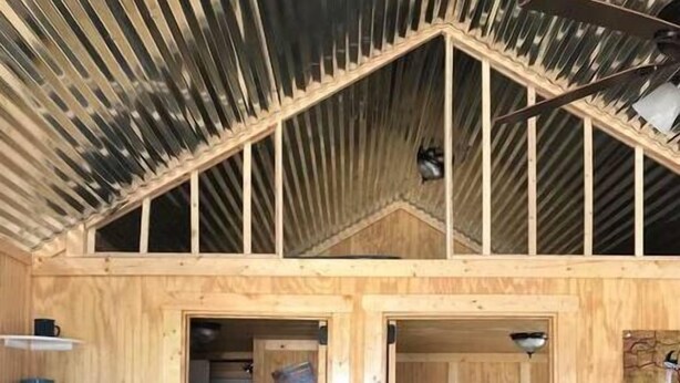 A wooden cabin with a loft bedroom, a kitchen with a sink, and a ladder leading to the loft.