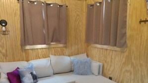 A cozy room with a beige sectional sofa, a small table, and a wooden wall.