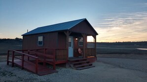 Une petite cabane en bois dotée d’un porche et d’un pont de bois menant à celle-ci.