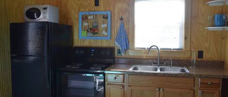 A compact kitchen with a refrigerator, stove, and sink.