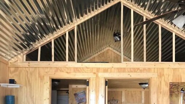 Une petite cabane en bois avec une chambre à coucher en mezzanine, une cuisine équipée d’un évier et une échelle menant à l’espace de couchage supérieur.