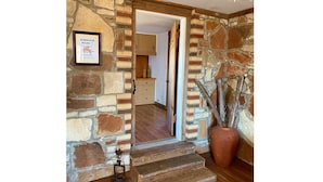 Un intérieur aux murs de pierre, avec un escalier en bois menant à une pièce.