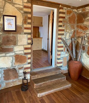 A stone-walled interior with a wooden staircase leading to a room. - Entire home hosted by D'Ann (Evant)