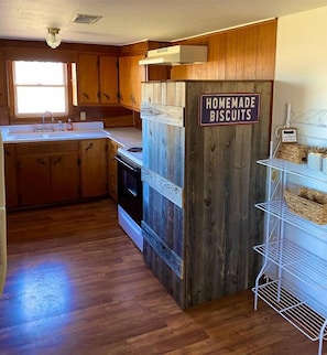 A kitchen with wooden cabinets, a sink, and a sign that reads "HOMEMADE BISCUITS".