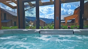 Ein Whirlpool mit Blick auf Holzhäuser und Berge im Hintergrund.