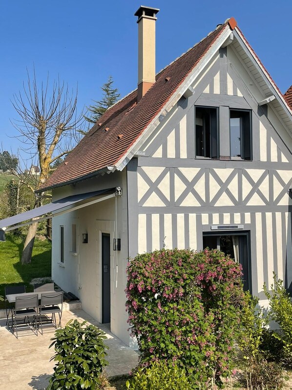 A two-story house with a gabled roof, a chimney, and a balcony.