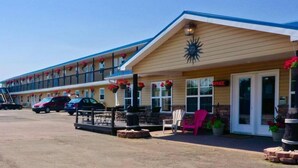 A motel with a covered front porch, outdoor seating, and a sign indicating an office. - Parlee Beach Motel (Shediac)