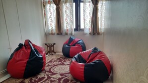 Une pièce avec trois fauteuils en forme de poire sur un tapis à motifs, une petite table en bois et une fenêtre avec des rideaux.