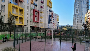 A multi-story residential building with balconies, a fenced playground, and a clear sky. - Luxury Apartment in Tbilisi | 24/7 Security | Prime Location (T'bilisi)