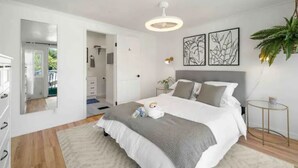Une chambre à coucher avec un lit, des tables de chevet, un miroir et des œuvres d’art accrochées au mur.