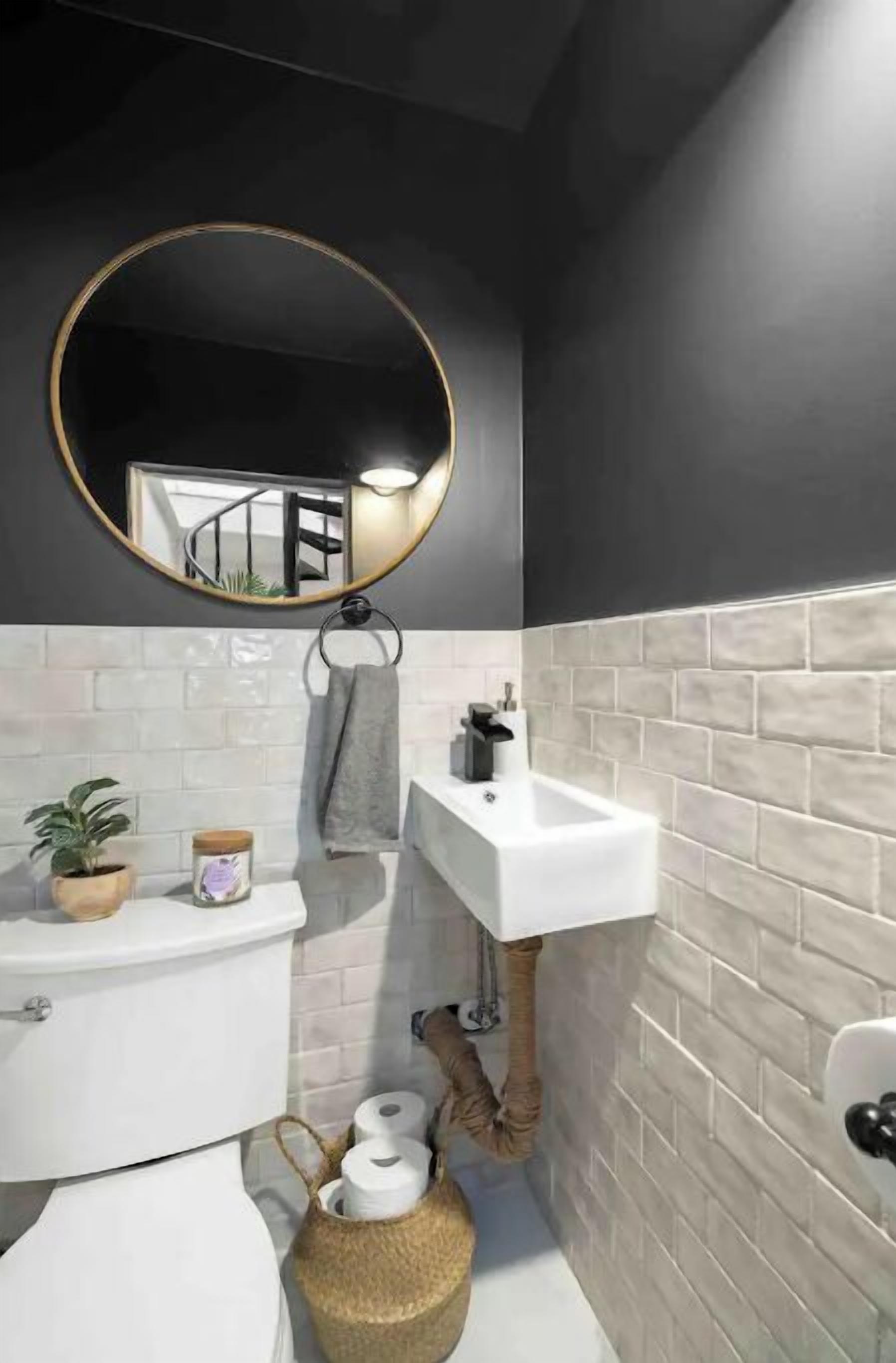 Un bany modern amb un mirall rodó, un lavabo blanc i un suport per a tovalloles.