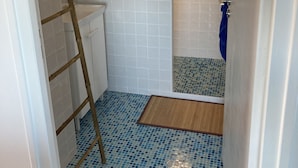 Ein Badezimmer mit Dusche, Toilette und kleinem Fenster.