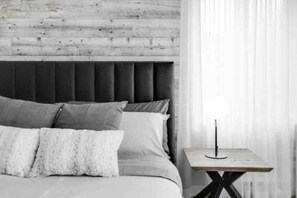 A bedroom with a bed, pillows, a bedside table, and a lamp. - Luxury Retreat CITQ 308338 (Mont-Tremblant)