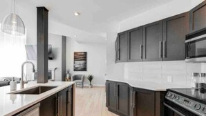 Una cocina moderna con armarios oscuros, una estufa de acero inoxidable y una encimera blanca.
