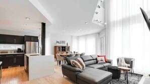 Un espacio moderno de estar con cocina, comedor y un amplio sofá seccional gris.