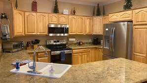 Una cocina con armarios de madera, electrodomésticos de acero inoxidable, encimeras de granito y un fregadero.