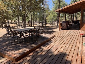 A wooden deck with a table and chairs, surrounded by trees.