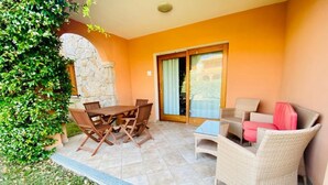 Un patio con una mesa y sillas de comedor, un sofá y una pared de piedra.
