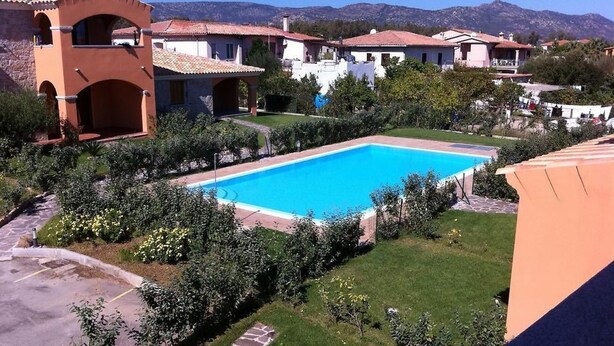 Una piscina rodeada por un jardín bien cuidado con una vista despejada de las montañas al fondo.