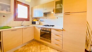 Una cocina compacta con estufa a gas, horno, microondas y una ventana sobre el fregadero.