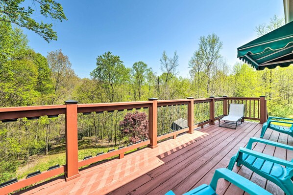 A wooden deck with a railing, outdoor chairs, and a view of a forest. - Cadiz Abode w/ Decks, Fire Pit, & Lake Access (Cadiz)