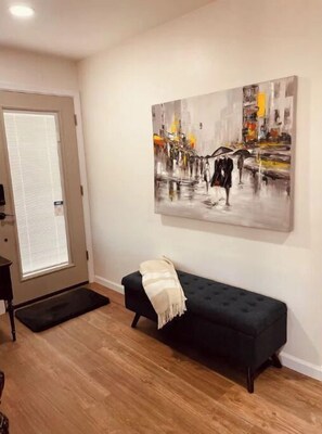 Relax in a stylish living room with a sofa, abstract cityscape art, and a wooden floor.