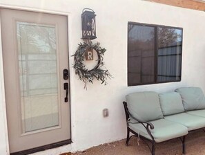 Access the building through the door with a glass panel and metal handle, adjacent to a decorative wreath and a window with a view.