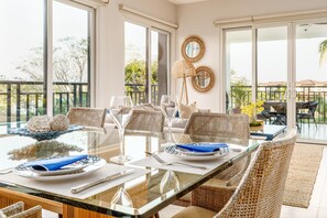 Enjoy meals in this dining area with a glass-top table and wicker chairs, surrounded by a balcony with a view.