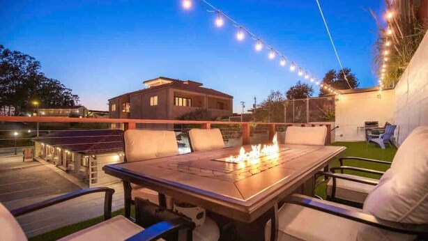 Eine Terrasse im Freien mit Feuerstelle, Sitzgelegenheiten und Lichterketten.