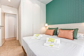 A hotel room with a bed, pillows, a wall with a green textured pattern, and a door.