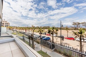 A balcony with a view of a parking lot, palm trees, and buildings in the distance.