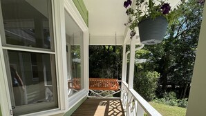 Une terrasse en bois avec une balustrade blanche et un pot de fleurs suspendu.