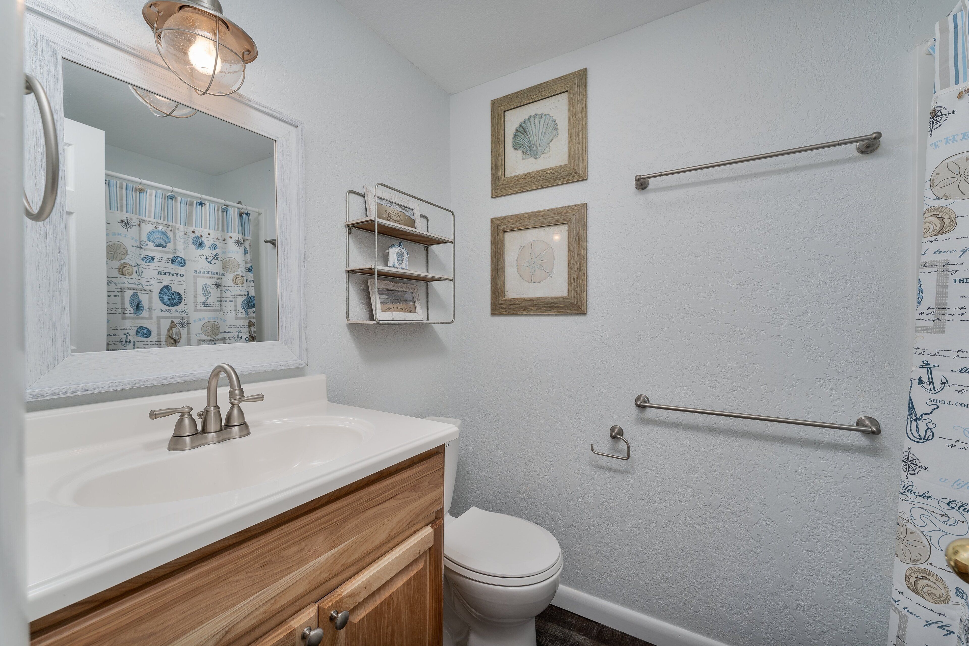 Une salle de bain avec un lavabo blanc, un meuble-lavabo en bois, des toilettes et un espace douche.