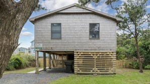 A two-story building with a covered parking area and a wooden fence.